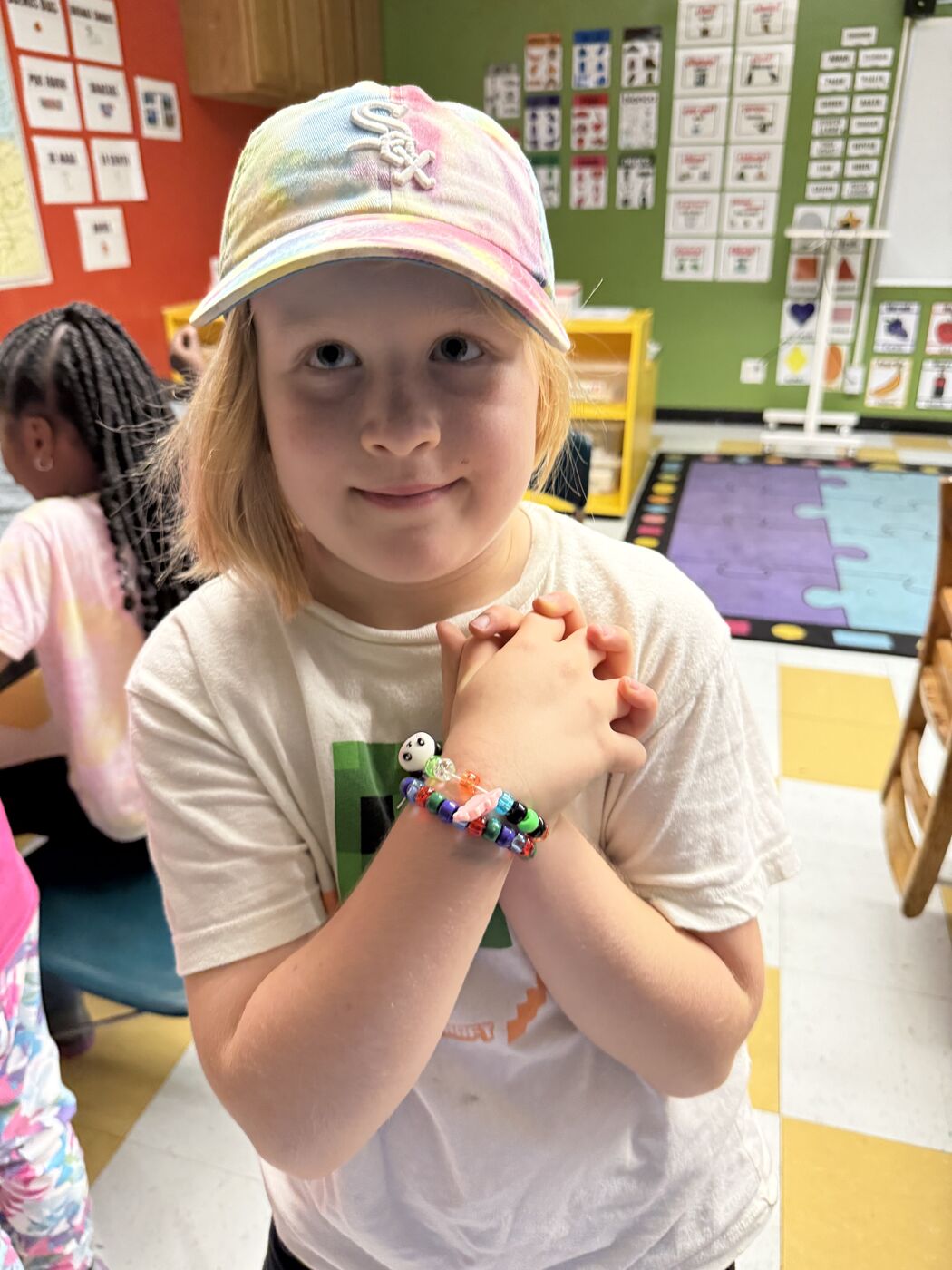 Student proudly showing off two beaded bracelets she made